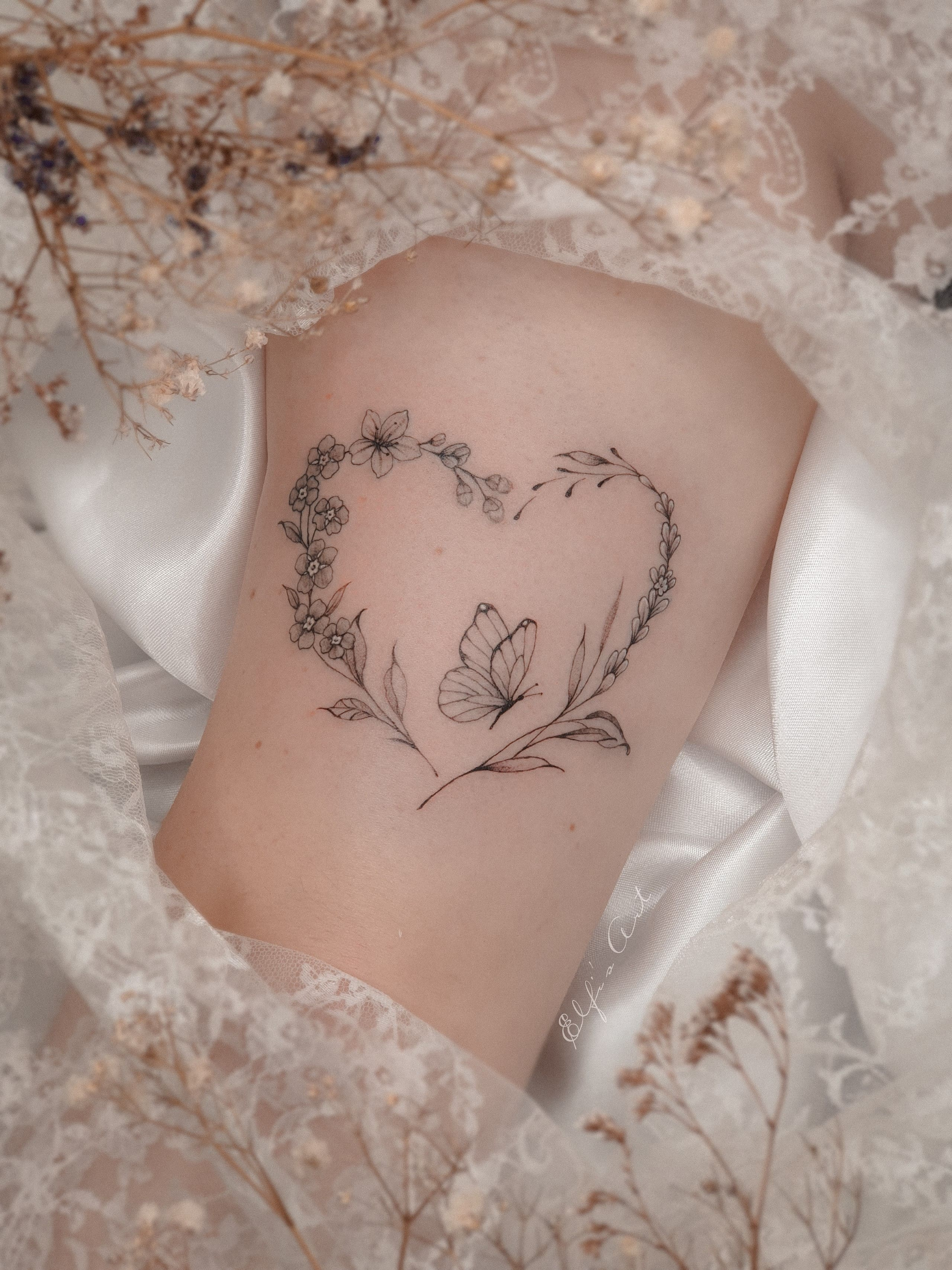 floraler Herzkranz mit Schmetterling Tattoo
